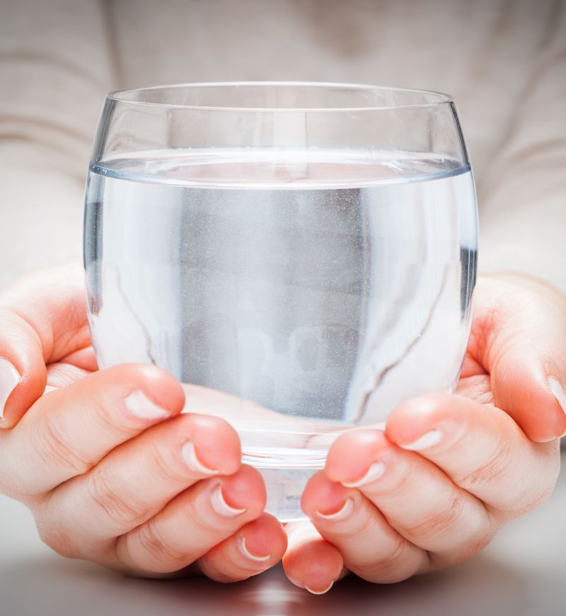 Hands holding a glass of clean water