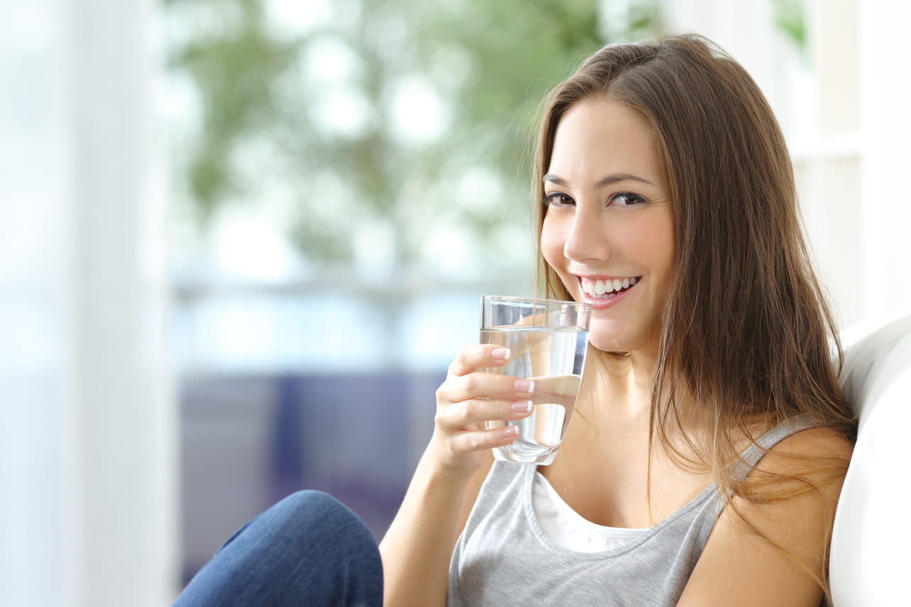 Women drinking water sitting on a couch at home