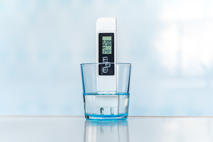TDS measurement of water. Electronic pH meter in a glass of water. poor water quality, high values of salt impurities,
