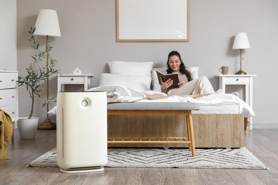 Air purifier against woman reading book in bedroom