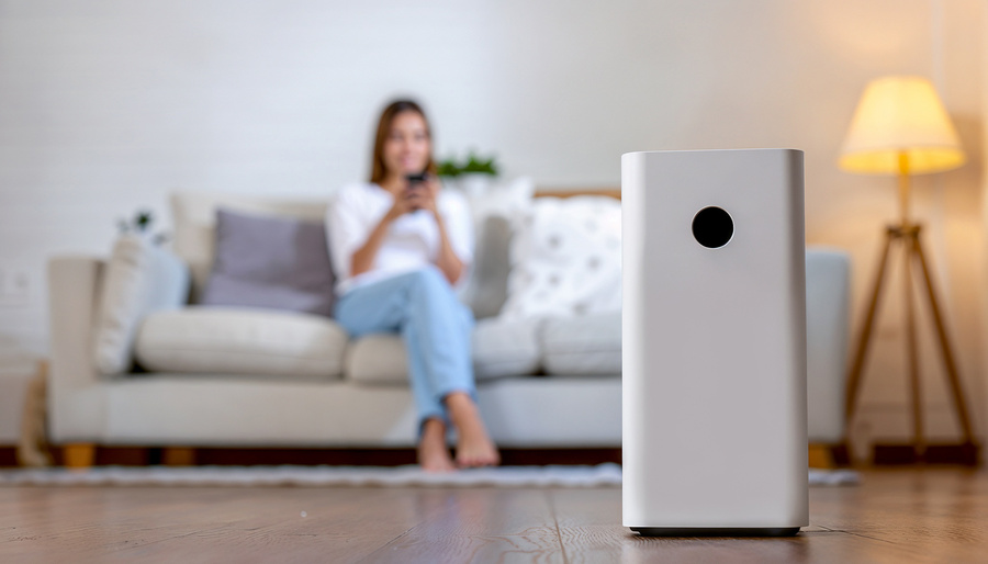 Air purifier dust filter clean and health air Air purifier against blurred woman using the phone on sofa in living room