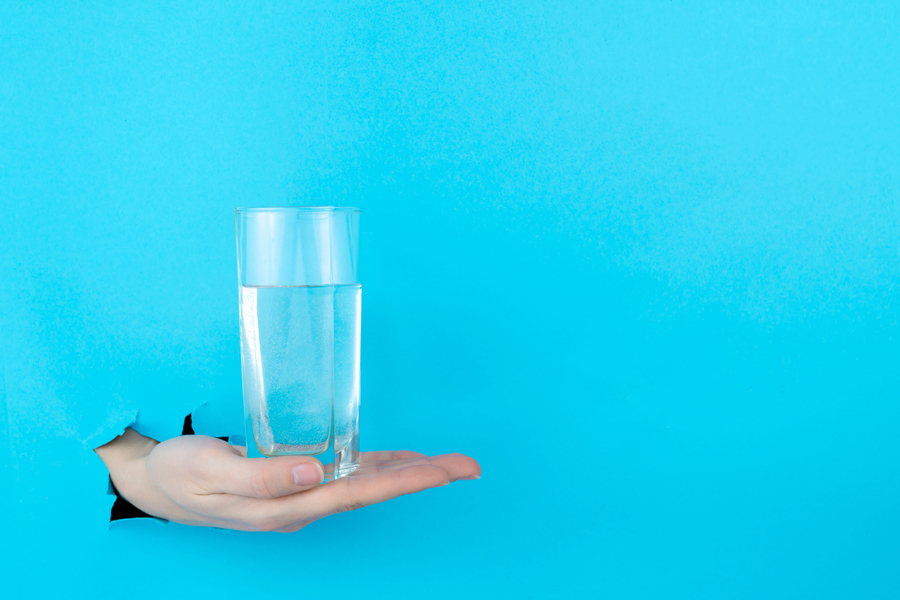 Female hand is holding is holding glass of pure water
