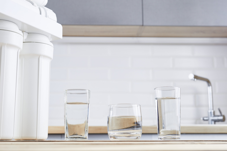 A glass of clean water and filter cartridges on a home kitchen