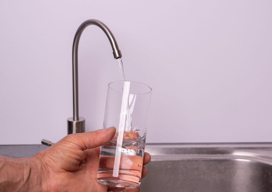 hand pouring a glass of water from filter tap