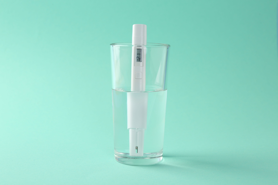 Nitrate tester in glass of water on turquoise background